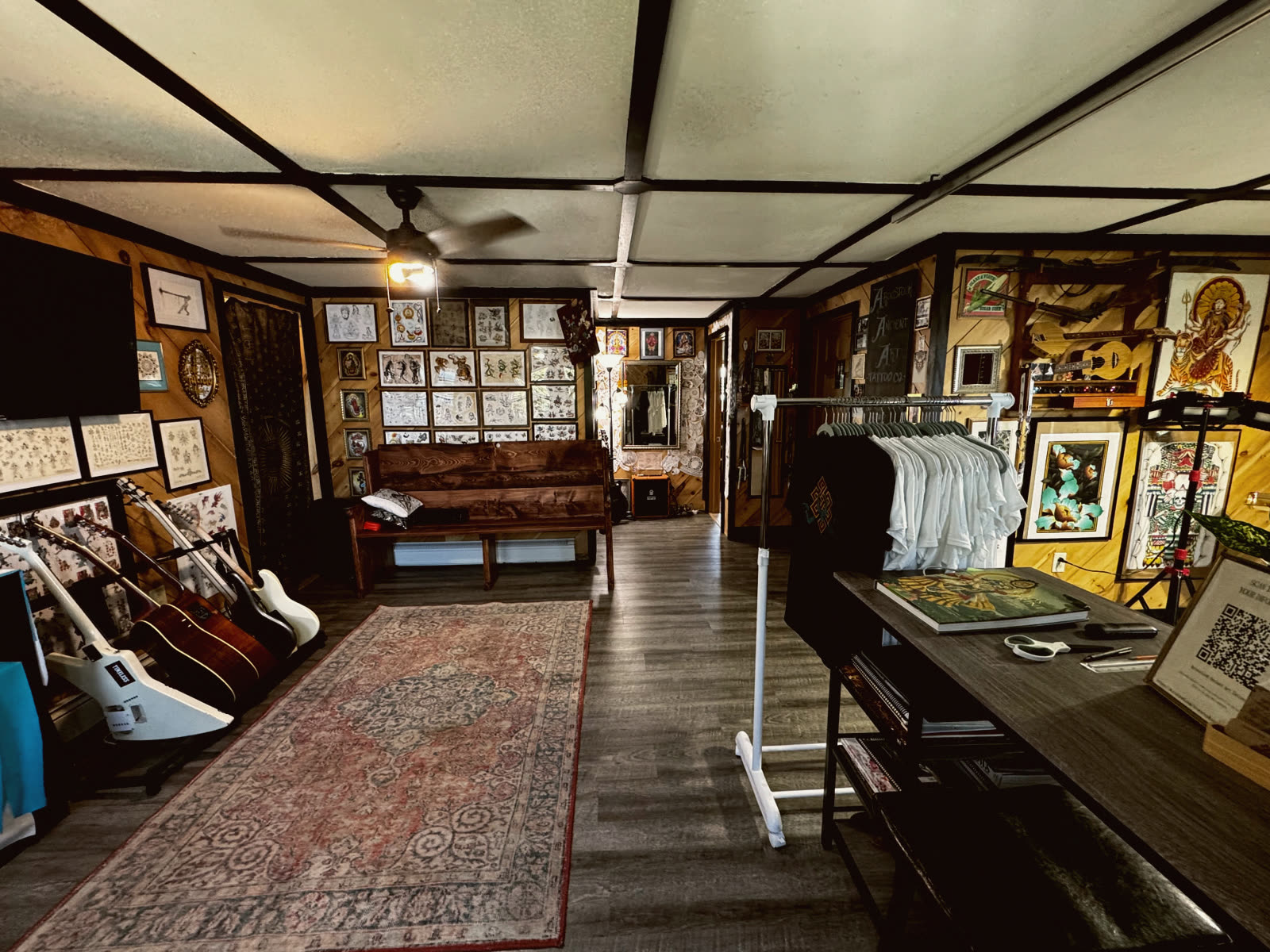 The lounge at Aroostook Ancient Art: a wooden bench, guitars, and walls of framed flash