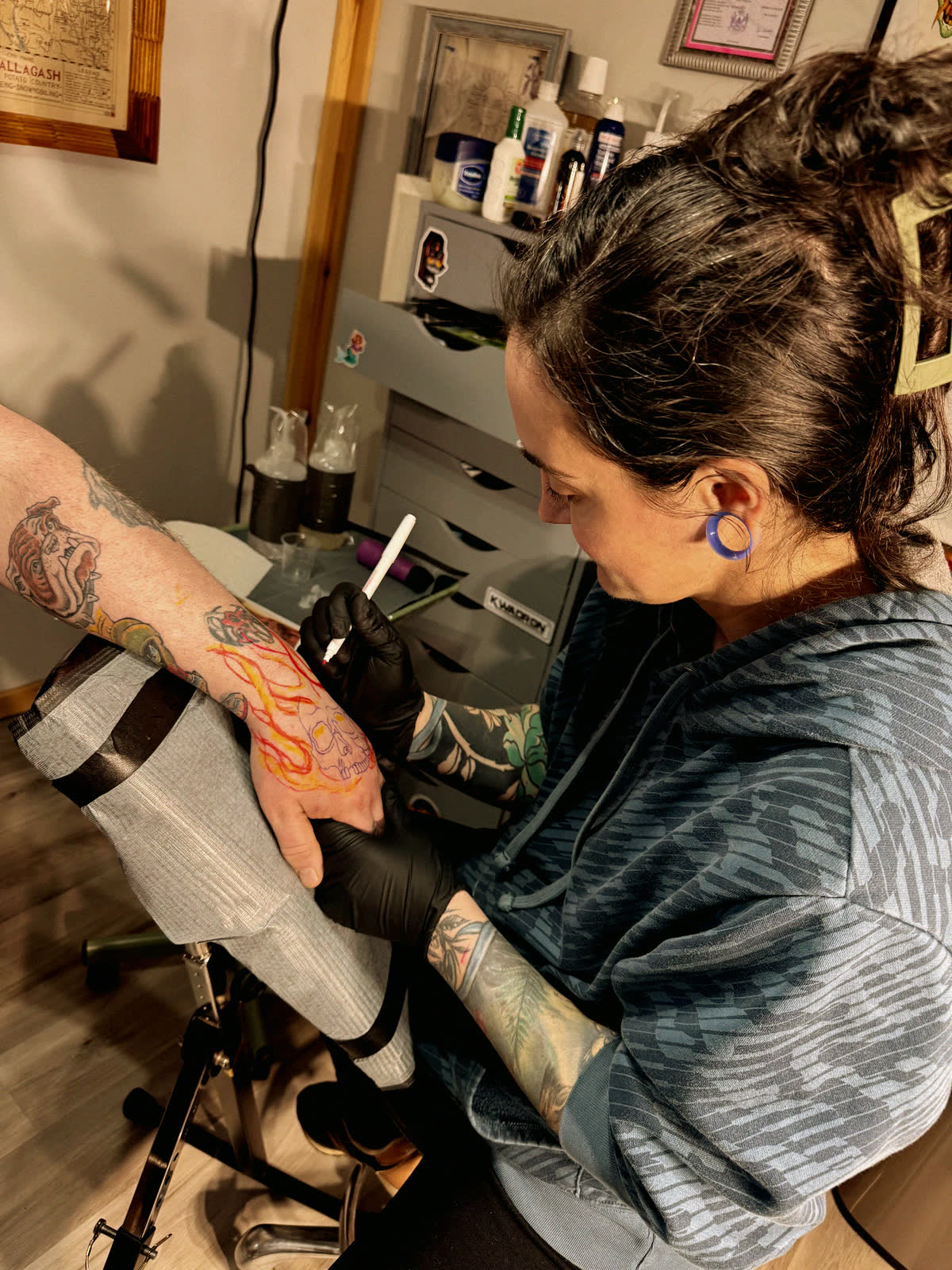 Cait tattooing a client's hand at Aroostook Ancient Art