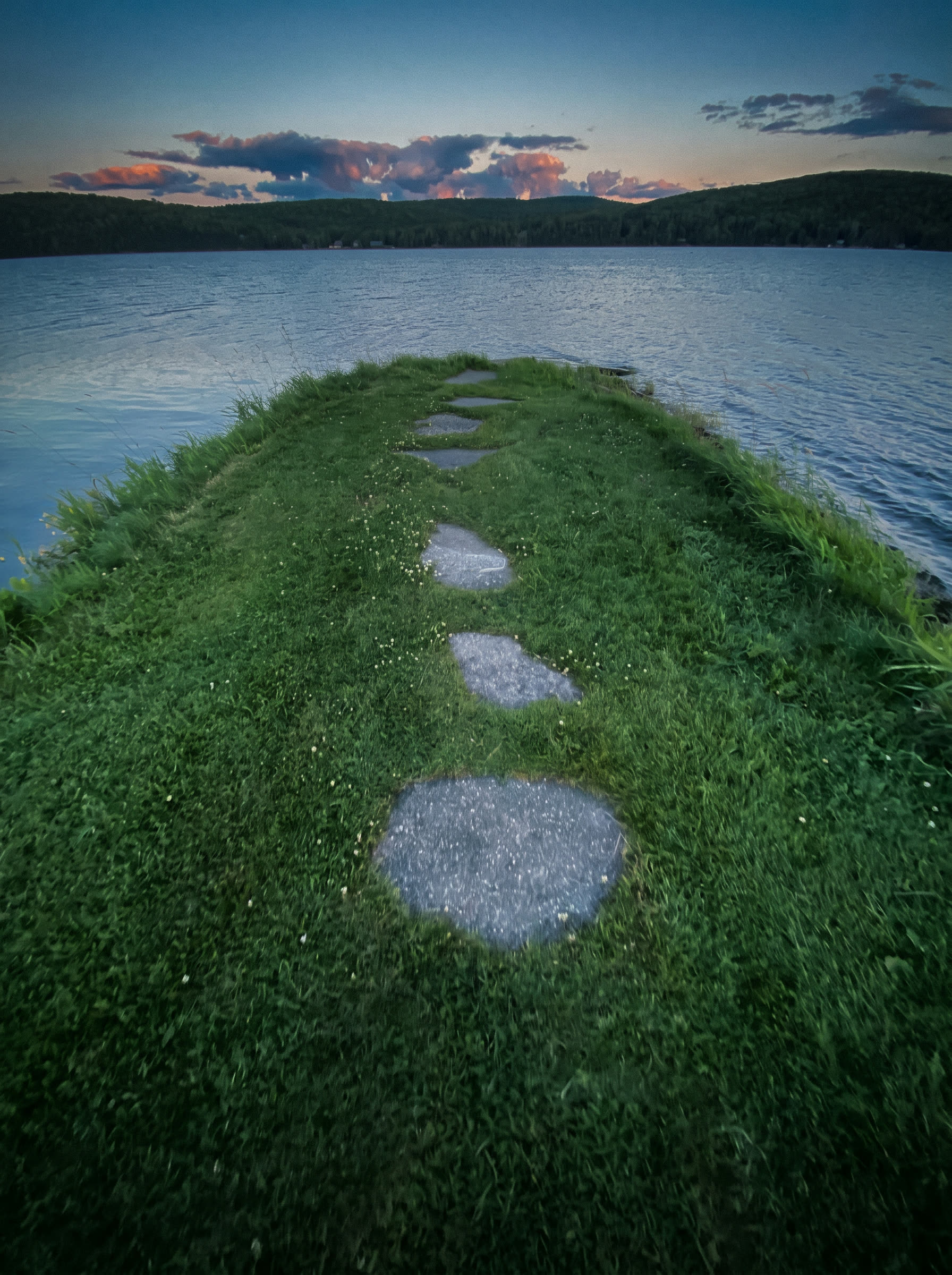 A grassy point reaching into Long Lake in Sinclair, Maine at dusk